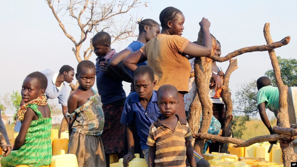 A group of children and adults gather around a bore-hole in the Bidi bidi refugee settlement in Bidi bidi, Uganda, Dec. 10, 2016.