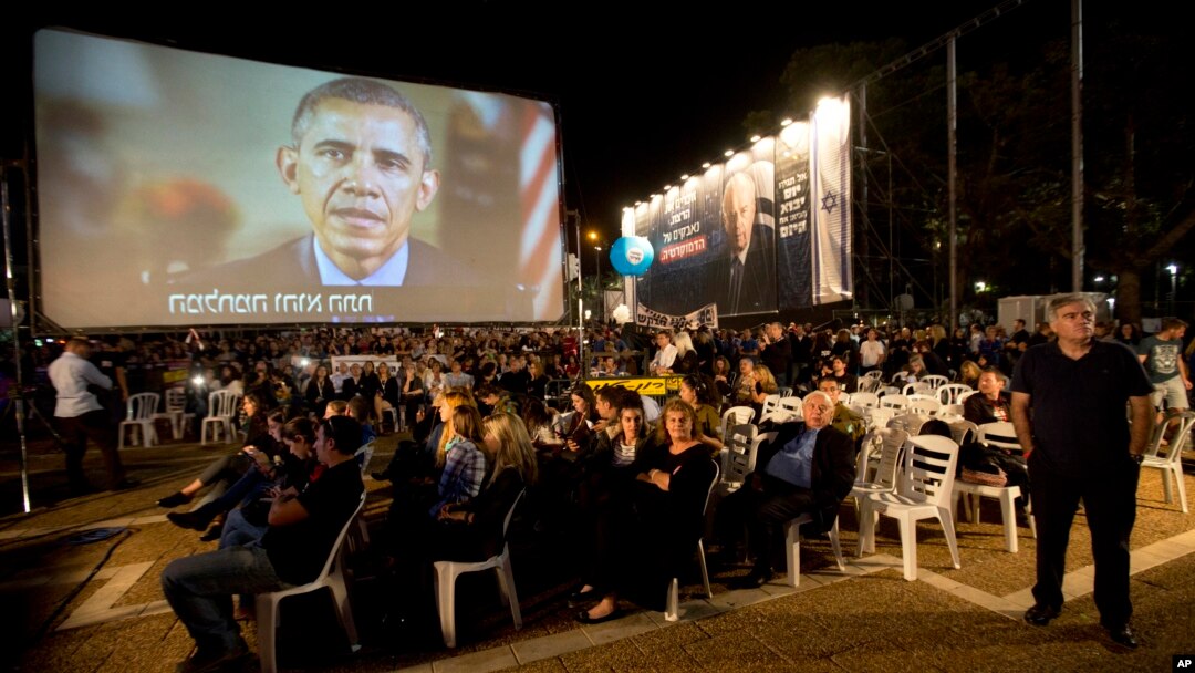 President Barack Obama, on a video monitor, addresses the gathering during a rally in Tel Aviv, Israel, marking 20 years since the assassination of former Israeli Prime Minister Yitzhak Rabin, Oct. 31, 2015.