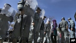 An Afghan woman protester walks past as policemen stand guard during a protest against September's parliamentary poll in Kabul, Afghanistan, 02 Nov. 2010.