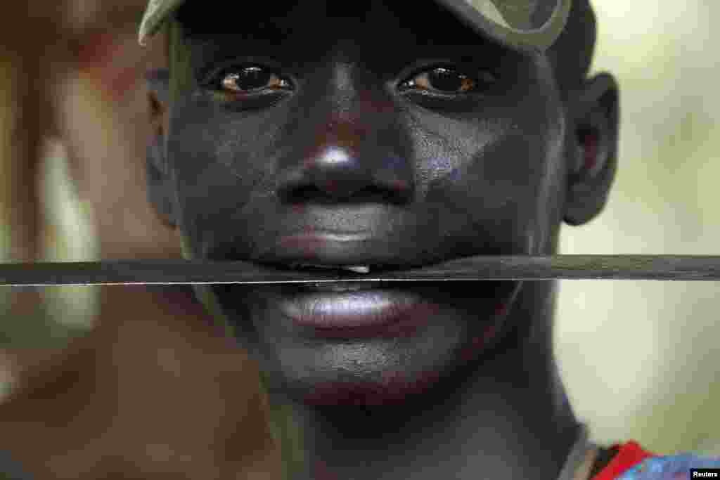 Un combattant de la milice chrétienne anti-balaka tient une machette entre ses dents à l&rsquo;état-major de son mouvement dans la bourgade de Boeing du Nord de Bangui, une zone près de l&rsquo;aéroport international de Boeing. Le 22 février 2014. 