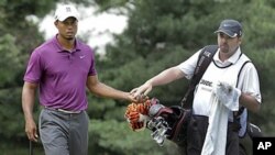 Tiger Woods takes the ball from his caddie Bryon Bell on the first green during first round action at the Bridgestone Invitational golf tournament at Firestone Country Club in Akron, Ohio, August 4, 2011