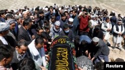 Afghan men prepare victims' coffins for a mass funeral ceremony after yesterday's explosion in Kabul, Afghanistan, May 9, 2021. 