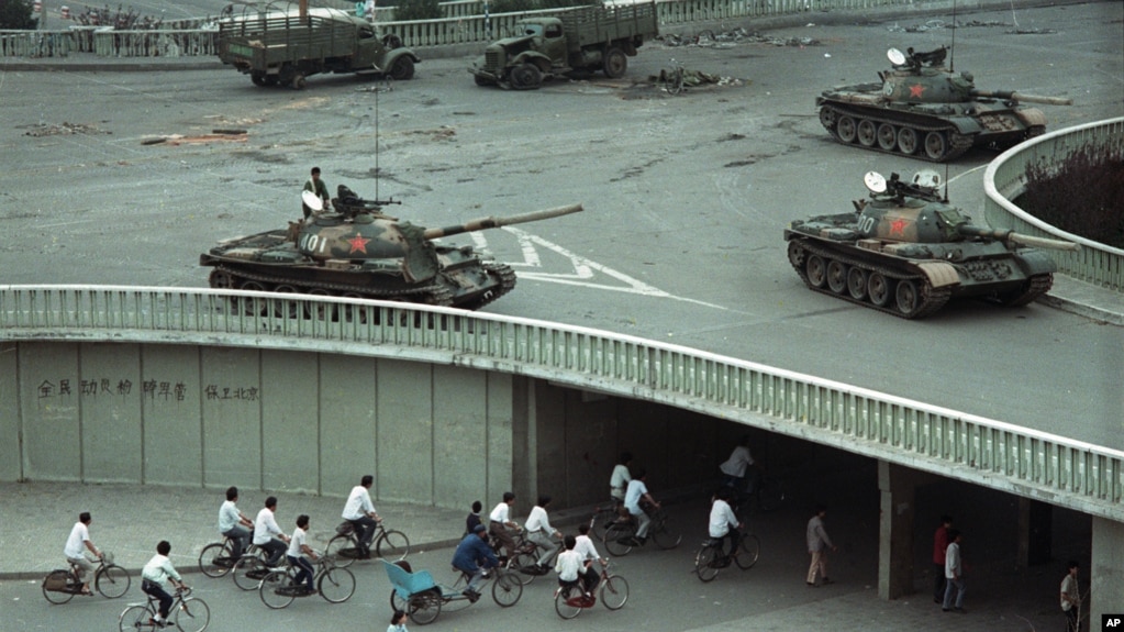 1989年6月6日星期二上午，在中国北京，天安门广场大屠杀发生两天后，自行车乘客稀少地穿过一条隧道，上面是天桥上部署的军用坦克。（美联社资料照片）(photo:VOA)