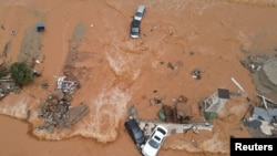 Debris and damaged cars are seen on a flooded seaside road during heavy rainfall at the village of Gournes on the island of Crete, Greece, Nov. 10, 2020.