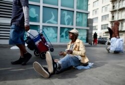 A woman sits on downtown Los Angeles' Skid Row, March 6, 2013.
