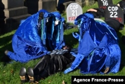 Performers from the Blue Rebels conduct a mock funeral ceremony at the 'Glasgow Necropolis' to symbolize what they see as the failure of the COP26 process, in Glasgow, Scotland, Britain, Nov. 13, 2021.