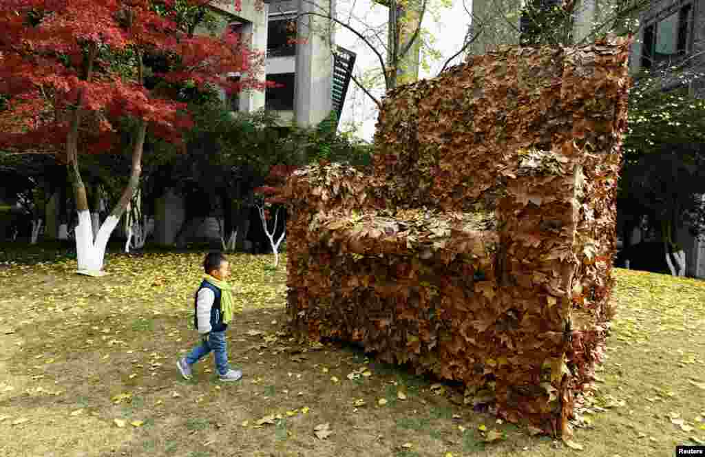 Seorang anak melewati kursi sofa yang dibuat dari daun kering untuk meningkatkan kesadaran lingkungan di Hangzhou, Zhejiang, China.