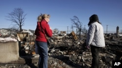 Bà Cathy O'Hanlon nhìn đống đổ nát của căn nhà bị đốt cháy còn lại của cô ấy về nhà với một người bạn ở Breezy Point, quận Queens, New York, Nov 14, 2012.