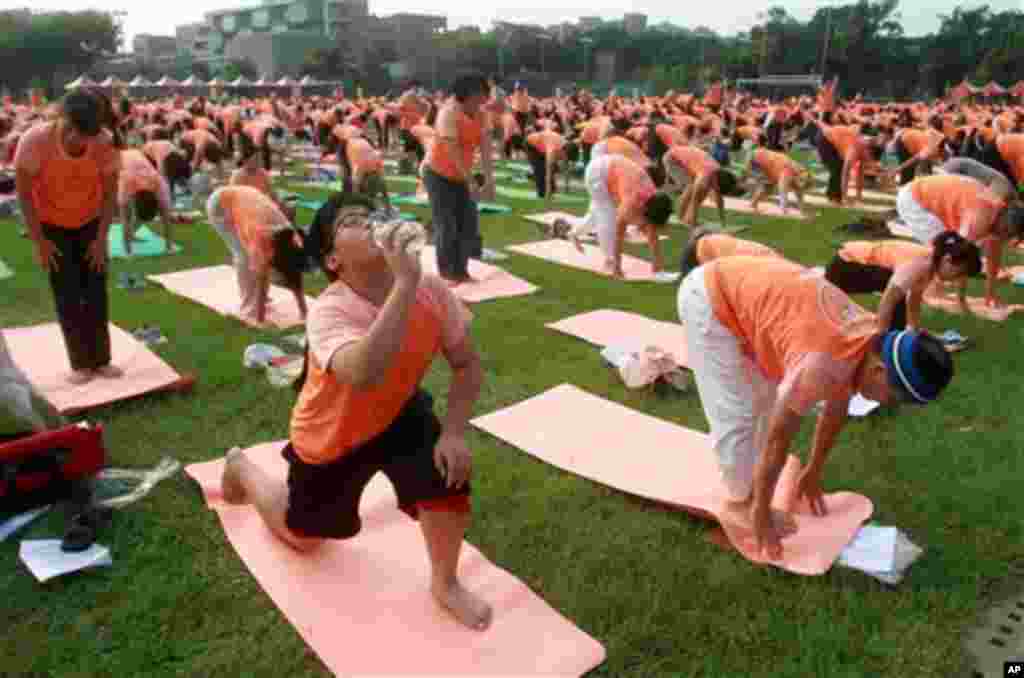 A boy drinks water as Taiwanese perform yoga at the start of International Yoga Day in Taipei, Taiwan, Sunday, June 21, 2015. Equipped with yoga mats and humming the sounds of Om, over two thousand people in Taipei city performed the 108 rounds of the Sun