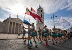 Lithuanian people take part in a traditional relay race Vilnius-Riga-Tallinn dedicated to the 30th anniversary of the Baltic Way at the Cathedral Square in Vilnius, Lithuania, Friday Aug. 23, 2019.