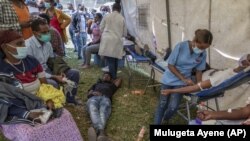 A man lies down after giving blood at a blood drive in support of the country's military, at a stadium in the capital Addis Ababa, Ethiopia Thursday, Nov. 12, 2020. (AP Photo/Mulugeta Ayene)