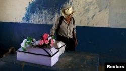 A man observes the remains of Petrona Chavarria and Vilma Ramos, who died in the El Mozote massacre, prior to their burial in the town of Jocoatique, El Salvador, Dec. 11, 2016. 