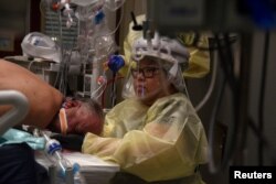 Teresa Nguyen, a respiratory therapist, treats a patient inside a room for people with COVID-19 at a hospital in Hutchinson, Kan., Nov. 20, 2020.