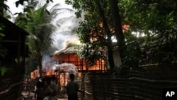 People look on a house engulfed in flames in Sittwe, Burma, June 11, 2012.