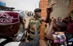 A policeman argues with a supporter of opposition leader Kizza Besigye at the gates of his party headquarters, before police who had surrounded it raided the building, in Kampala, Uganda, Feb. 19, 2016.