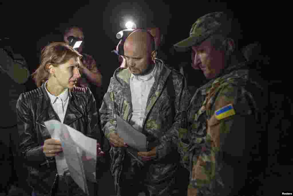 Representatives of the Ukrainian government forces (center and right), and of pro-Russian rebels (left) talk before exchanging prisoners-of-war (POWs), north of Donetsk, eastern Ukraine, Sept. 12, 2014.&nbsp;