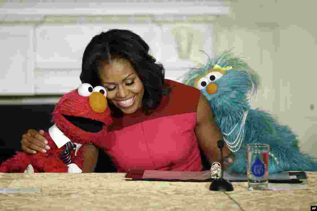 First lady Michelle Obama (center) with PBS Sesame Street character Elmo (left) and Rosita (right) as they help promote fresh fruit and vegetable consumption to kids in an event in the State Dining Room of the White House in Washington, Oct. 30, 2013.