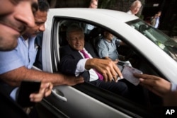 In this July 11, 2018 photo, Mexico's President-elect Andres Manuel Lopez Obrador receives a note from a man, as he leaves his headquarters in the Roma neighborhood of Mexico City.