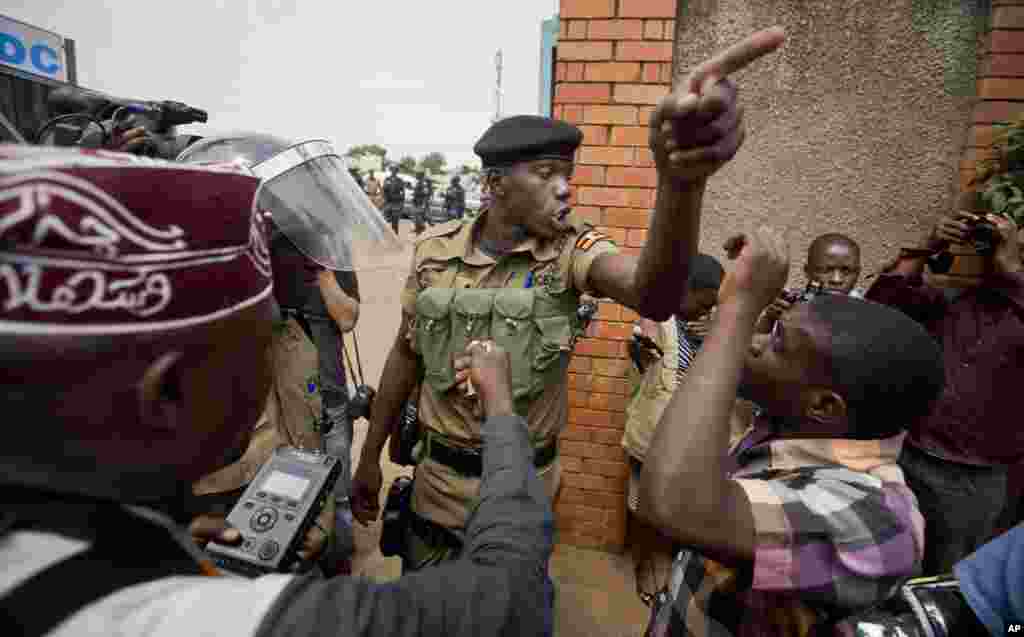 A policeman argues with a supporter of opposition leader Kizza Besigye at the gates of his party headquarters, before police who had surrounded it raided the building, in Kampala, Uganda.