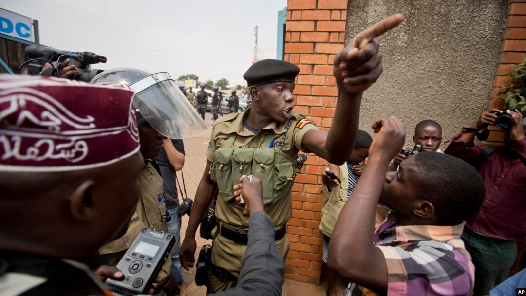 FILE - A policeman argues with a supporter of opposition leader Kizza Besigye at the gates of his party headquarters, before police who had surrounded it raided the building, in Kampala, Uganda, Feb. 19, 2016. 