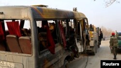 Seorang prajurit Afghanistan berdiri di samping bangkai bus yang terkena serangan bom bunuh diri di Kabul 26 Januari 2014. 