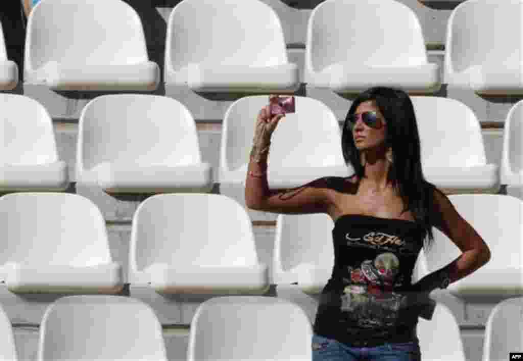 A woman takes pictures from the grand stand during the first free practice at the Yas Marina racetrack , in Abu Dhabi, United Arab Emirates, Friday, Nov. 11, 2011. The Emirates Formula One Grand Prix will take place on Sunday. (AP Photo/Luca Bruno)