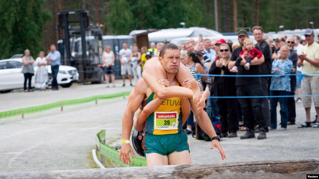  Vytauta Kirkliauskas dari Lithuania menggendong istrinya, Neringa Kirkliauskiene, saat balap lari dalam Kejuaraan Dunia Menggendong Istri 2018 di Sonkajarvi, Finlandia, 7 Juli 2018.