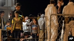 FILE - Migrants wait to disembark from the Italian Navy Ship "Grecale" at Pozzallo harbor, Sicily, May 13, 2014. 