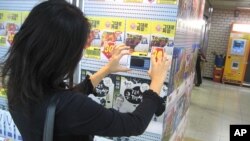 A young woman uses her smartphone to shop for groceries in Seoul's Seolleung subway station.