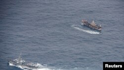 Ecuadorian Navy vessels surround a fishing boat after detecting a fishing fleet of mostly Chinese-flagged ships in an international corridor that borders the Galapagos Islands' exclusive economic zone, in the Pacific Ocean, August 7, 2020. Picture taken…