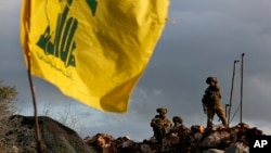 FILE - Israeli soldiers stand guard next to cameras at their new position in front of a Hezbollah flag, near the Lebanese southern border village of Mays al-Jabal, Lebanon, Dec. 13, 2018.
