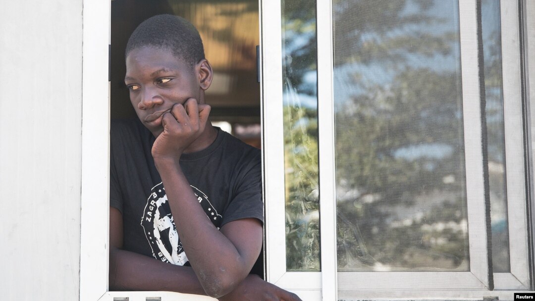 A man looks out from a window as people fleeing from violence after the murder of a local gang leader camp out in the courtyard of Cite Soleil's town hall, in Port-au-Prince, Haiti, Dec. 7, 2019. 