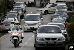 A car, center, believed to be carrying former Malaysian Prime Minister Najib Razak leaves his private resident in Kuala Lumpur, Malaysia, May 18, 2018. Malaysian police confiscated a few hundred designer handbags and dozens of suitcases containing cash, jewelry and other valuables as part of a corruption and money-laundering investigation into Najib.