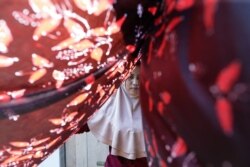 A mangrove batik worker dries a batik cloth in Klaces village, Cilacap, Central Java province, Indonesia, November 4, 2021. Picture taken November 4, 2021. REUTERS/Ajeng Dinar Ulfiana