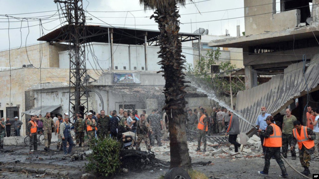 In this photo released by the Syrian official news agency SANA, Syrian security forces and firefighters gather at the scene of an explosion, in the central city of Homs, Syria, Tuesday, May 23, 2017.