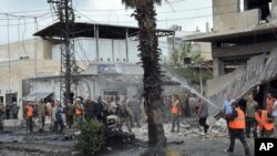 In this photo released by the Syrian official news agency SANA, Syrian security forces and firefighters gather at the scene of an explosion, in the central city of Homs, Syria, Tuesday, May 23, 2017.