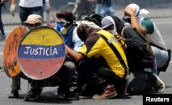 FILE - Opposition supporters use a shield that reads "Justice" as they clash with security forces during a rally against Venezuela's President Nicolas Maduro in Caracas, Venezuela, April 26, 2017.