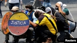 FILE - Opposition supporters use a shield that reads "Justice" as they clash with security forces during a rally against Venezuela's President Nicolas Maduro in Caracas, Venezuela, April 26, 2017.