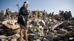Pemberontak Houthi memeriksa bangunan perumahan yang hancur akibat serangan udara Saudi di dekat bandara Sanaa, Yaman, Kamis (26/3).