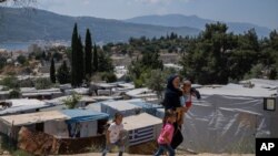 An Afghan woman with her three children walk outside the perimeter of the refugee camp at the port of Vathy on the eastern Aegean island of Samos, Greece, June 11, 2021.