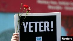 FILE - A member of the Journalists Union of Turkey holds a placard reading "Enough!" during a demonstration to mark World Press Freedom Day in central Istanbul, May 3, 2017. 