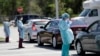 Healthcare workers screen people at a drive-through COVID-19 testing site, March 20, 2020, at the Doris Ison Health Center in Miami, Florida.