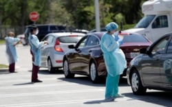 FILE - Healthcare workers screen people at a drive-through COVID-19 testing site, March 20, 2020, at the Doris Ison Health Center in Miami, Florida.