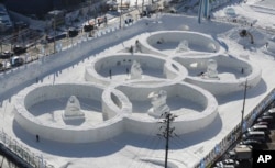 Visitors tour near the snow sculpture in the shape of the Olympic rings displaying at the Daegwanryung Snow festival in Pyeongchang, South Korea, Feb. 3, 2017.