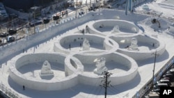 FILE - Visitors tour near the snow sculpture in the shape of the Olympic rings displayed at the Daegwanryung Snow festival in Pyeongchang, South Korea, Feb. 3, 2017.