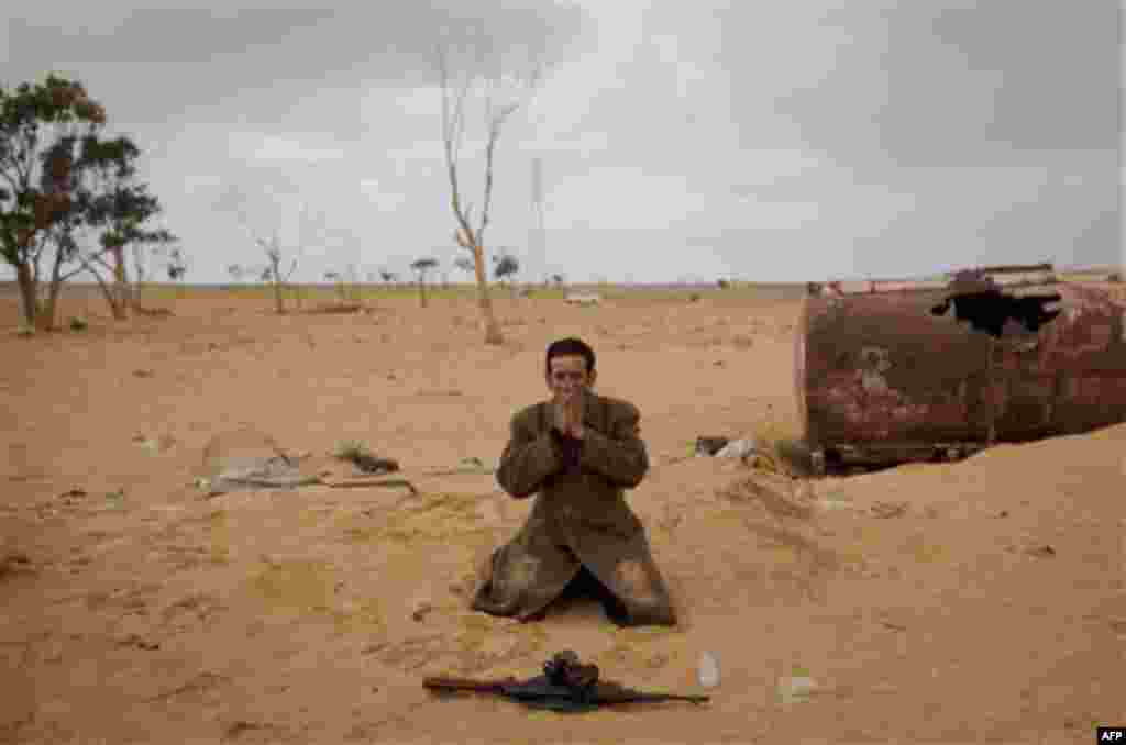 A Libyan rebel prays next to his gun on the frontline of the outskirts of the city of Ajdabiya, south of Benghazi, eastern Libya, Monday, March 21, 2011. The international military intervention in Libya is likely to last "a while," a top French official s