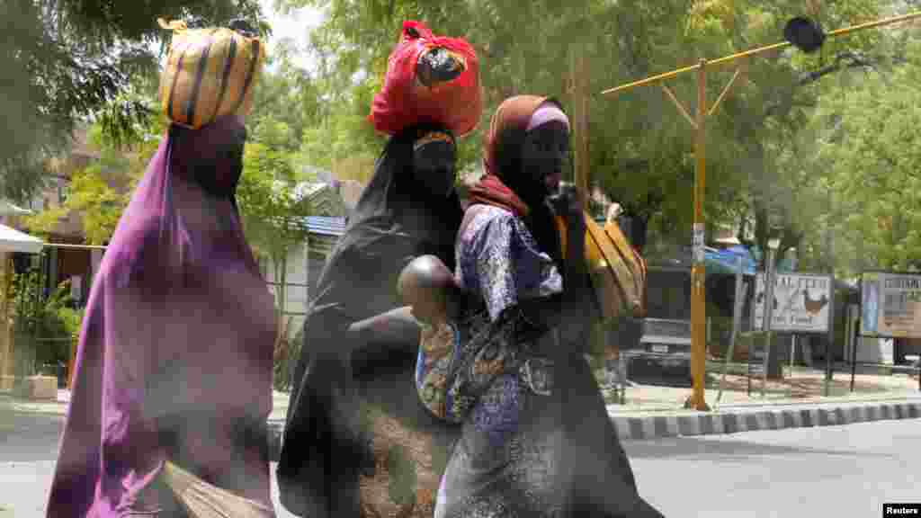 Women attempt to cross Jos Road with their belongings, after the military declared a 24-hour curfew over large parts of Maiduguri in Borno State May 19, 2013.