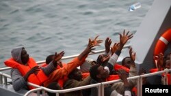 Des migrants secourus sur le pont d'un bateau de patrouille des forces armées de Malte (AFM) tentent de récupérer une bouteille d'eau qui leur jetée après l'arrivée du navire à la base Escadron maritime de l'AFM au Haywharf dans le port Marsamxett de La Valette, le 22 janvier 2015.