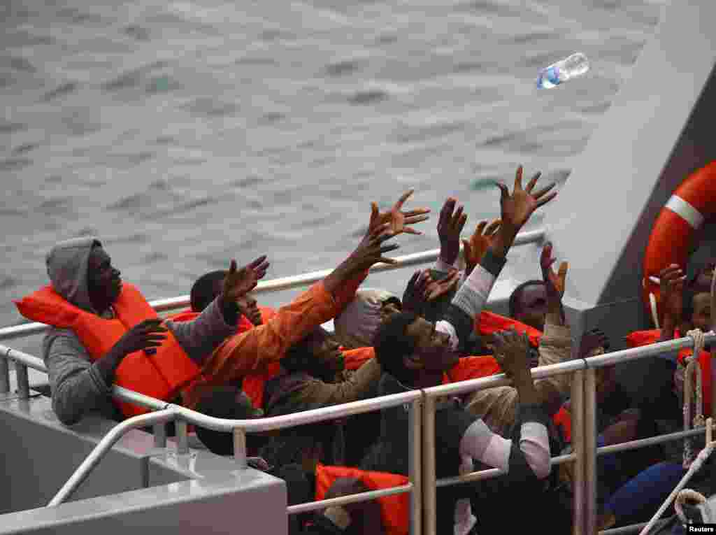 Rescued migrants on the deck of an Armed Forces of Malta (AFM) patrol boat reach out for a bottle of water after arriving at the AFM&#39;s Maritime Squadron base at Haywharf in Valletta&#39;s Marsamxett Harbor. A Maltese patrol boat rescued about 80 migrants off the island, but another 20 people were feared to have died.