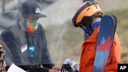 File- An employee is protected by a plexiglass shield while processing a skier at the reopening of Arapahoe Basin Ski Resort, which closed in mid-March to help in the effort to stop the spread of the new coronavirus May 27, 2020 in Keystone, Colo.